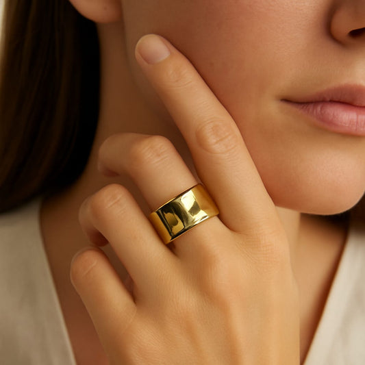 Close-up of a hand wearing a gold ring with a neutral background