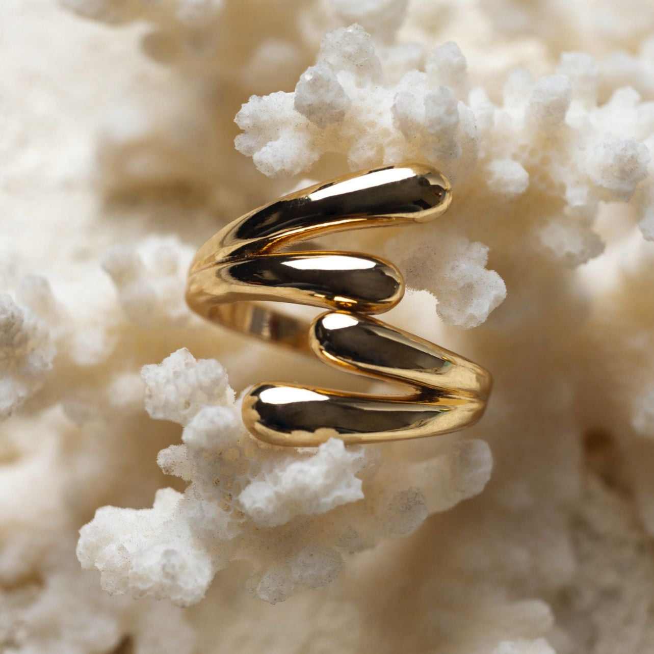 Gold spiral ring on a textured beige background