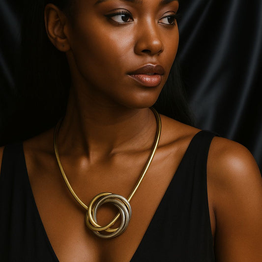 Woman wearing a gold and silver intertwined statement necklace against a black outfit.