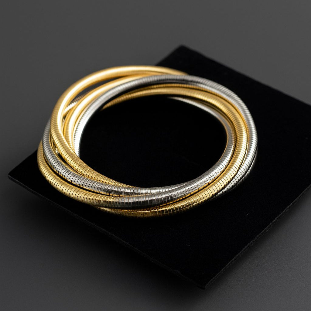 Stacked metallic wrap chain cum bangle in gold and silver tones displayed on a black velvet pad.