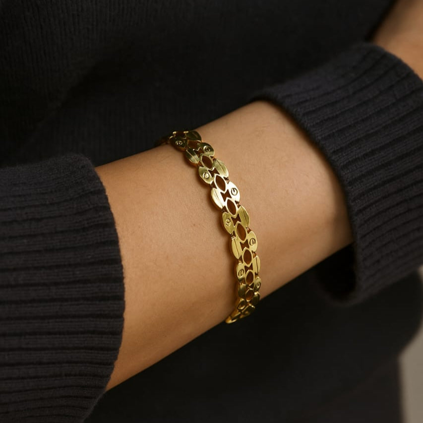 Gold chain bracelet on a wrist with a black sleeve