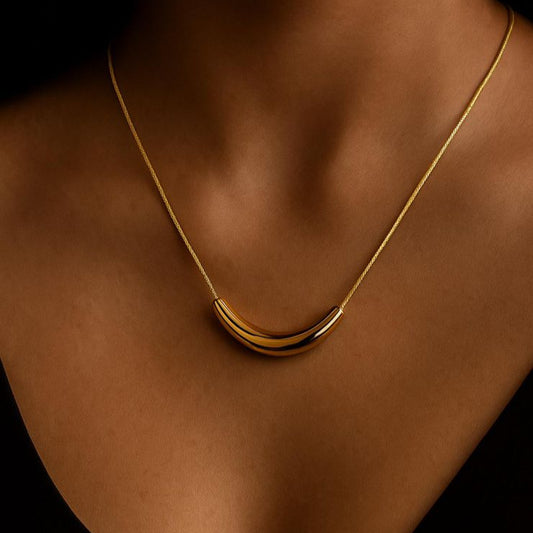 Gold necklace on a person's neck against a dark background