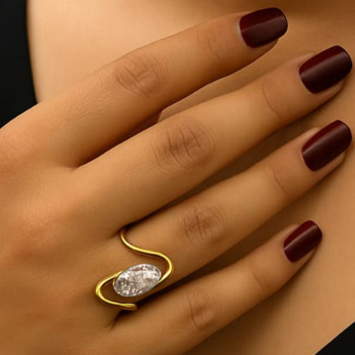 Close-up of a hand wearing a gold ring with a large diamond on a dark background