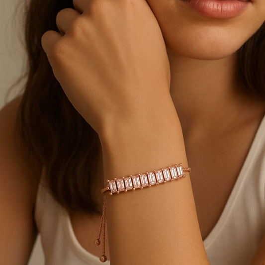 Close-up of a woman's wrist wearing a rose gold bracelet against a neutral background