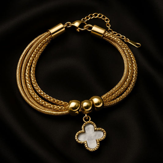 Gold bracelet with a clover charm on a black background