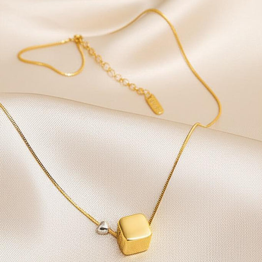 Gold necklace with a square pendant on a beige fabric background