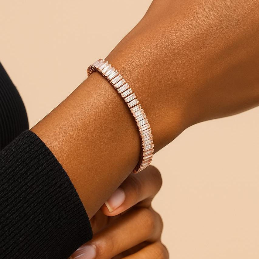 Rose gold bracelet on a wrist against a beige background
