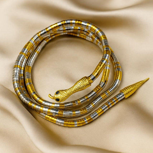 Decorative snake-shaped object with gold and silver accents on a beige fabric background