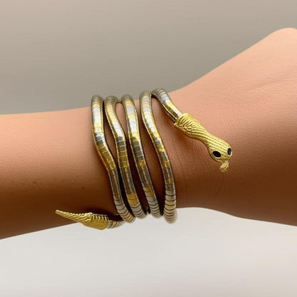 Gold snake-shaped bracelet on a wrist against a neutral background